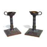 A pair of Indo-Persian enamelled copper candlesticks, the drip trays formed as oil lamps, 16cms (6.