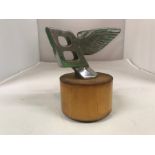 A Bentley Flying B car mascot, leaning forward, 10 cm, 4 inches wide, mounted on a plinth
