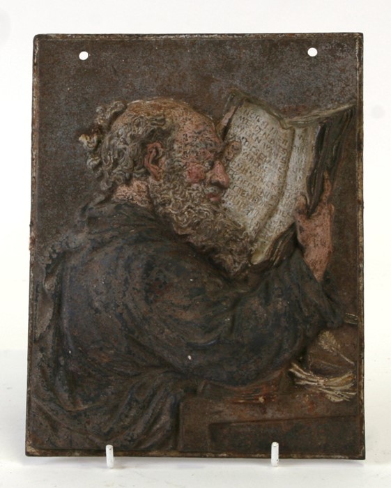 A cold painted cast iron plaque depicting a monk reading a manuscript, 16 by 21cms (6.25 by 8.