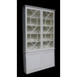 A pair of painted pine bookcases on cupboards, the pair of glazed doors enclosing a shelved interior