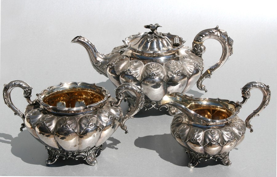 A William IV silver three-piece tea set of circular melon repousse form, with acanthus and flower