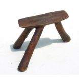 An African carved tripod stool carved from a single piece of wood, 23cms wide.