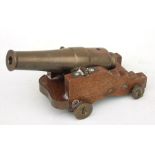 A late 19th century signal cannon with a bronze barrel mounted on a wooden carriage with bronze