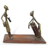 A pair of African tribal bronze / brass figures, one playing a drum, mounted on a hardwood base,