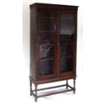 An oak bookcase on stand with a pair of glazed doors enclosing a shelved interior, 94cms wide.