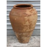 A large terracotta olive jar with wavy banded decoration, 50cms high.