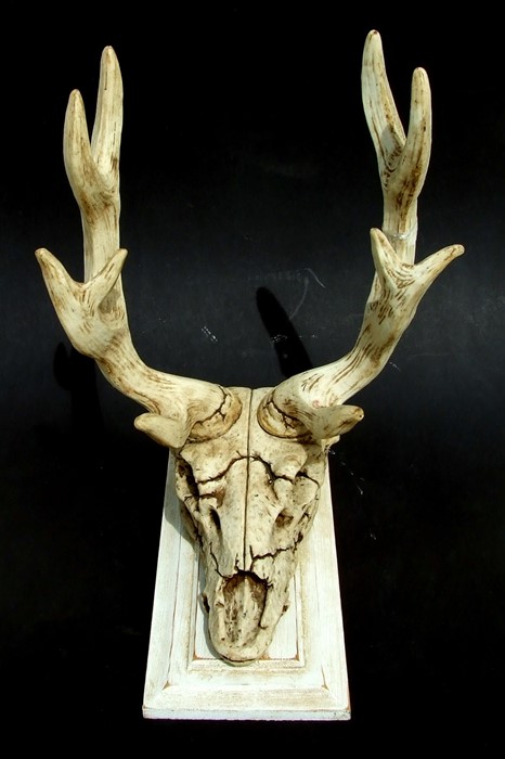 A resin antlered stag's skull sword stand mounted on a wooden plaque, 40cms high.