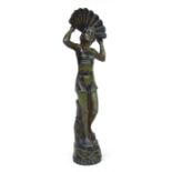 An Art Deco green patinated spelter figure of a scantily clad lady dancer holding aloft a peacock