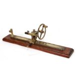 A brass thread winder mounted on a wooden base, 50cms wide.