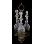 A Victorian silver plated three bottle stand with three decanters, 38cms wide.