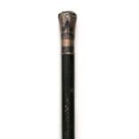 A hardwood walking cane with carved decoration and silver coloured metal pommel head with niello