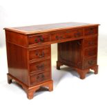 A reproduction yew wood pedestal desk with inset green leather top above an arrangement of nine