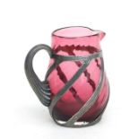 A cranberry cream jug with white metal overlay decoration, 9.5cms high.