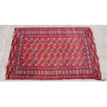 A Turkish rug with repeated geometric design on a red ground, 124 by 184cms.