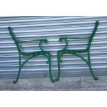 A pair of green painted metal bench ends.