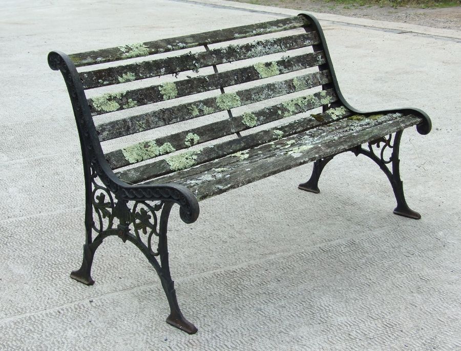 A well weathered garden bench with cast iron ends, 126cms wide.