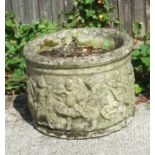 A reconstituted stone garden planter of cylindrical form, decorated with figures, 46cms diameter.