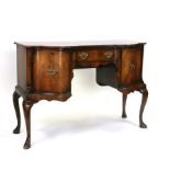A George III style serpentine fronted mahogany sideboard with central frieze drawer flanked by two