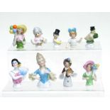 A quantity of novelty porcelain pin cushion half dolls to include a baby wearing a top hat.