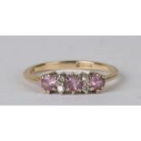 A 9ct gold dress ring set with three pink stones interspersed with diamonds, approx UK size 'K'.