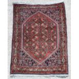 A Persian Bijar hand knotted rug with repeat foliate design on a red ground, 100 by 75cms.