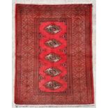A Persian Turkoman hand knotted rug with five central guls within stylised borders, on a red ground,