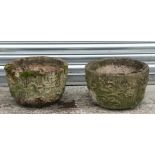 A pair of well weathered reconstituted stone planters with floral decoration, 38cms diameter (2).
