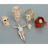 A carved ivory skull, 4cms high; together with similar carved heads and a Corpus Christi.