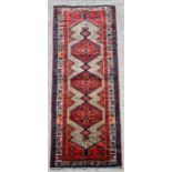 A Persian hand knotted Hamadan runner with stylised design on a red ground, 315 by 100cms.