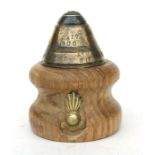 A WW1 brass Artillery Fuze mounted in a later turned oak desk mount with applied UBIQUE brass badge.