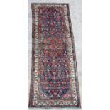 A Persian hand knotted Hamadan runner with stylised foliate design on a blue ground, 300 by 105cms.
