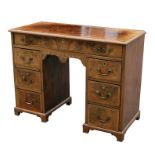 A Georgian style figured walnut kneehole desk, the crossbanded rectangular top above an