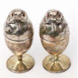 A pair of white metal (untested) novelty egg cups and covers in the form of chicks, 11cms high (2).