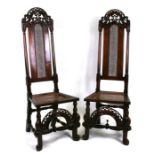 A pair of 17th century style walnut high back dining chairs with carved crest back rails, cane