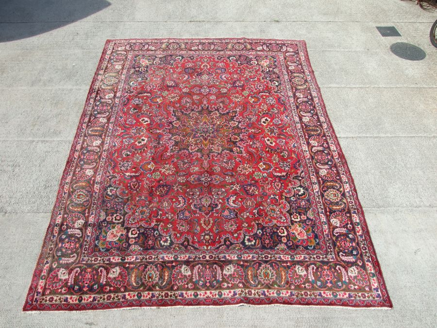 A Persian Mashad woollen hand knotted carpet with central foliate gul within foliate borders, on a