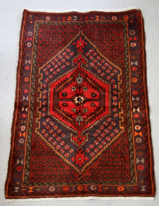 A Persian Hamadan woollen hand knotted rug with central gul within borders, 96 by 140 37.5 by