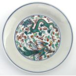 A Chinese Ducai shallow dish decorated with a dragon and phoenix chasing a flaming pearl amongst