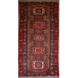 A Persian Azari hand knotted woollen runner with five stylised guls within floral borders, on a blue