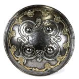 An Indian dhal hand held shield with silver inlay decoration, 30cms diameter.