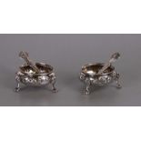 A pair of early Victorian silver cauldron shaped salts with repousse decoration, on three pad