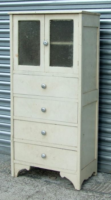 A painted pine kitchen cabinet with a pair glazed panelled doors above four drawers, on a shaped