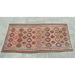 A kilim rug with repeating geometric patterns on a cream ground within a multi border, 140 by