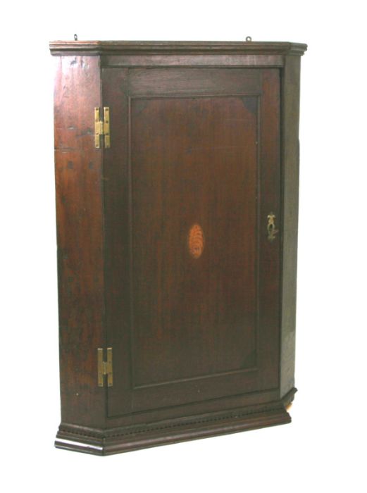 A 19th century oak hanging corner cupboard with single panelled door and shell inlaid decoration,