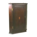 A 19th century oak hanging corner cupboard with single panelled door and shell inlaid decoration,