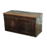 An 18th century and later oak chest with a carved frieze above a pair of carved panelled doors,