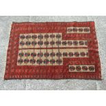 A Persian Baluch woollen hand knotted prayer rug with repeating motifs on a red ground, 84 by