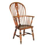 An elm Windsor elbow chair on turned legs joined by a stretcher.