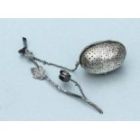 A Victorian silver coloured metal tea strainer in the form of an apple hanging from a branch, weight