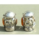 A pair of Art Nouveau style silver coloured metal and glass cylindrical pepperette with amber