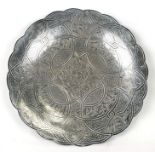 An Iznik white metal circular wavy edged tray with engraved decoration, on three ball feet, 25cms